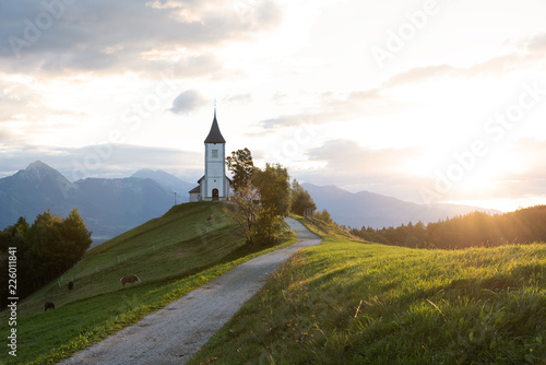 Church on the hill at sunrise. Beautiful scenery at Jamnik, Slovenia. Panoramic view of the Alps behind the church.