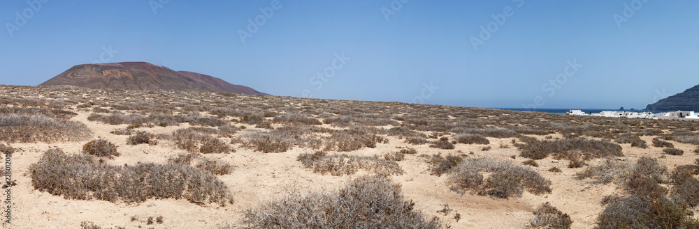 Lanzarote, Isole Canarie: strada sterrata, cespugli e paesaggio desertico con la Montagna Pedro Barba, il vulcano dell'isola La Graciosa