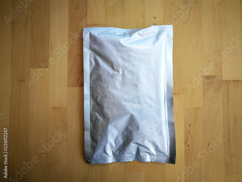 Blank Foil plastic pouch bag isolated on wooden background. copy-space.