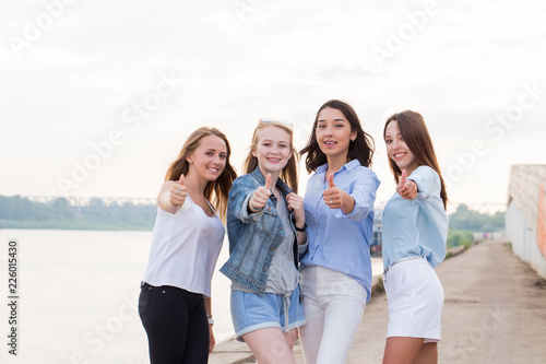 Happy group of female friends with thumbs up outdoor looking at camera and smile