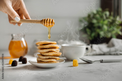 Stack of pancakes with honey syrup on wooden white background