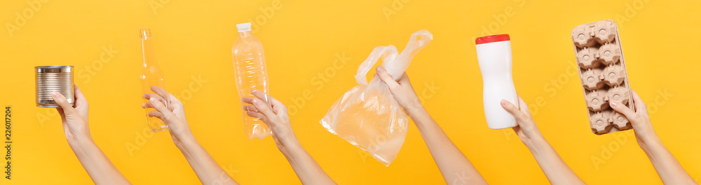 Close up hands hold set of recycling paper plastic glass metal objects isolated on yellow background. Stop nature garbage, ecology environment protection concept. Save planet Packaging template mockup - obrazy, fototapety, plakaty 