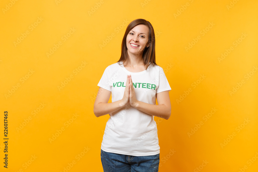 Portrait of happy smiling satisfied woman in white t-shirt with written inscription green title volunteer isolated on yellow background. Voluntary free assistance help, charity grace work concept. Portrait of happy smiling satisfied woman in white t-shirt with written inscription green title volunteer isolated on yellow background. Voluntary free assistance help, charity grace work concept.