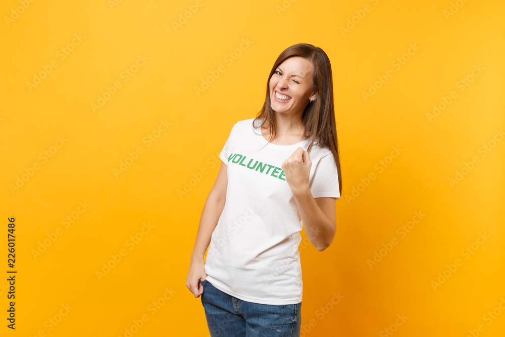 Portrait of happy overjoyed excited woman in white t-shirt with written inscription green title volunteer isolated on yellow background. Voluntary free assistance help, charity grace work concept. Portrait of happy overjoyed excited woman in white t-shirt with written inscription green title volunteer isolated on yellow background. Voluntary free assistance help, charity grace work concept.
