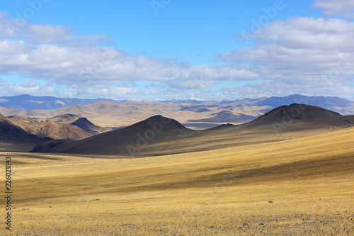 Landscape of winding dirt road through rolling hills of Western Mongolian steppe