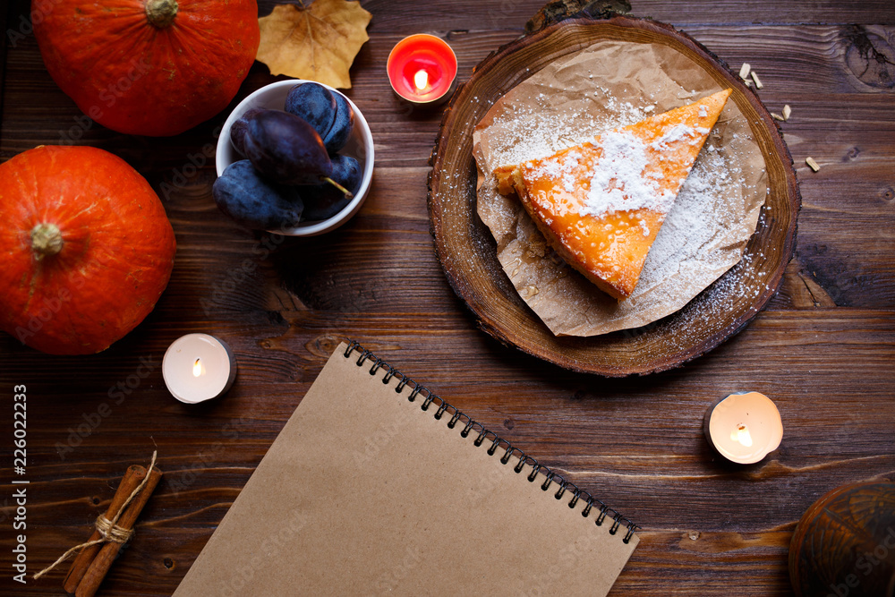 Notebook, pumpkin cheesecake, cooked at home, pumpkin, foliage, table lamp, vanilla on a wooden dark table. Autumn and winter cozy concept. Notebook, pumpkin cheesecake, cooked at home, pumpkin, foliage, table lamp, vanilla on a wooden dark table. Autumn and winter cozy concept.