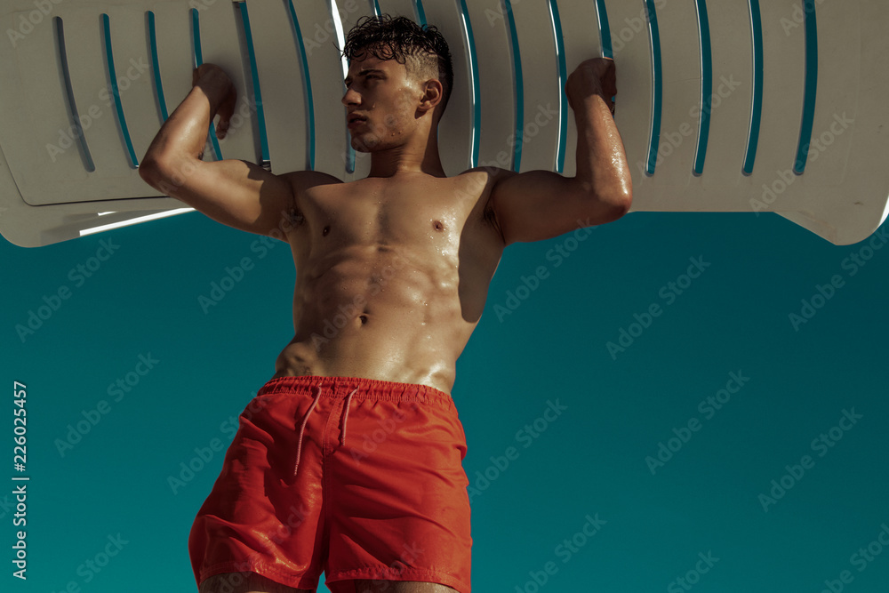 Φωτογραφία Strong face muscle male model in the open  summer shower on the vacation pool ba