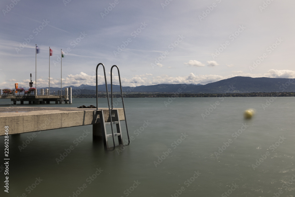 A long exposure of a dock in Switzerland with mountains in the back