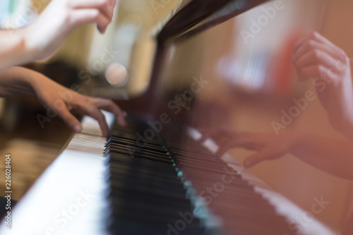 Hands of a person playing a brown grand piano