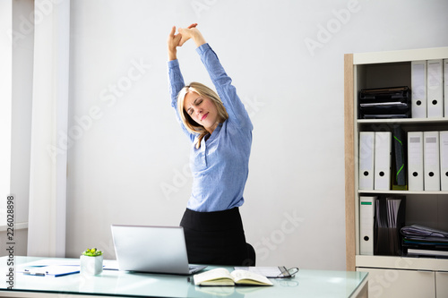 Businesswoman Stretching Her Arms At Workplace