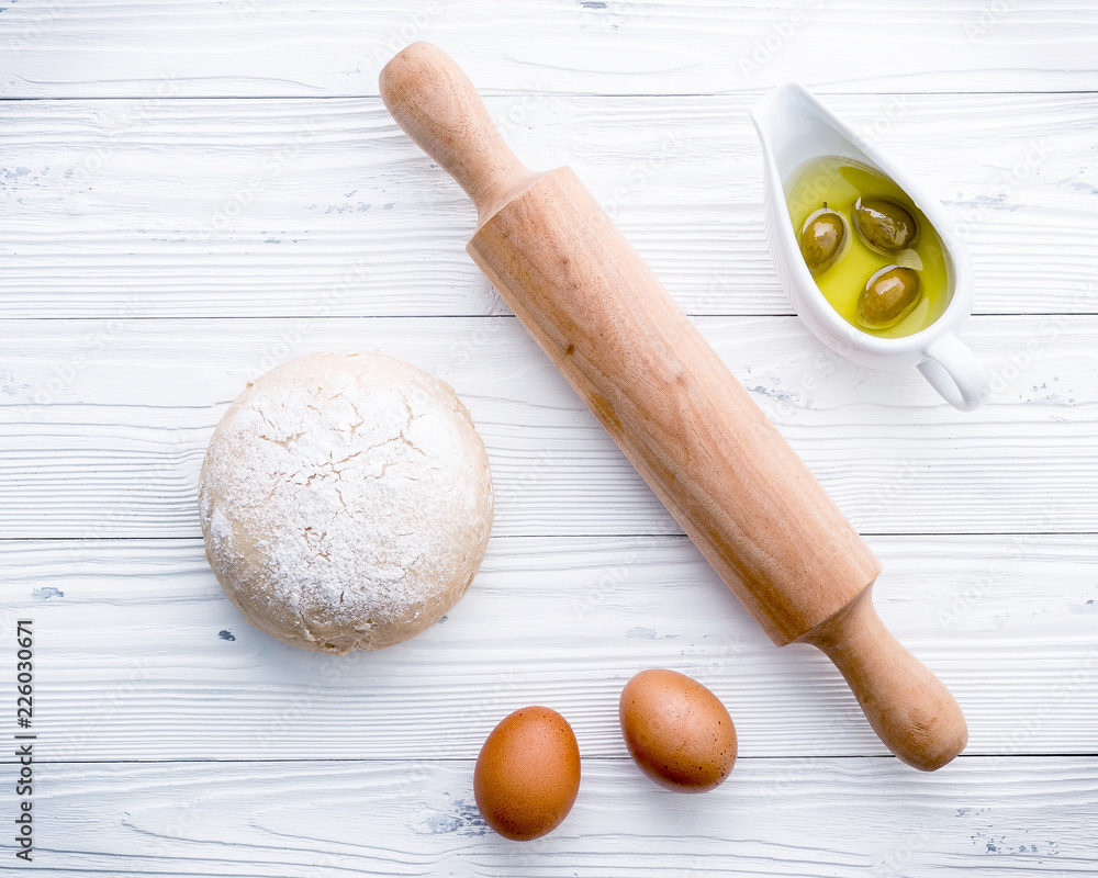 Raw pizza dough and rolling pin on wooden background Raw pizza dough and rolling pin on wooden background