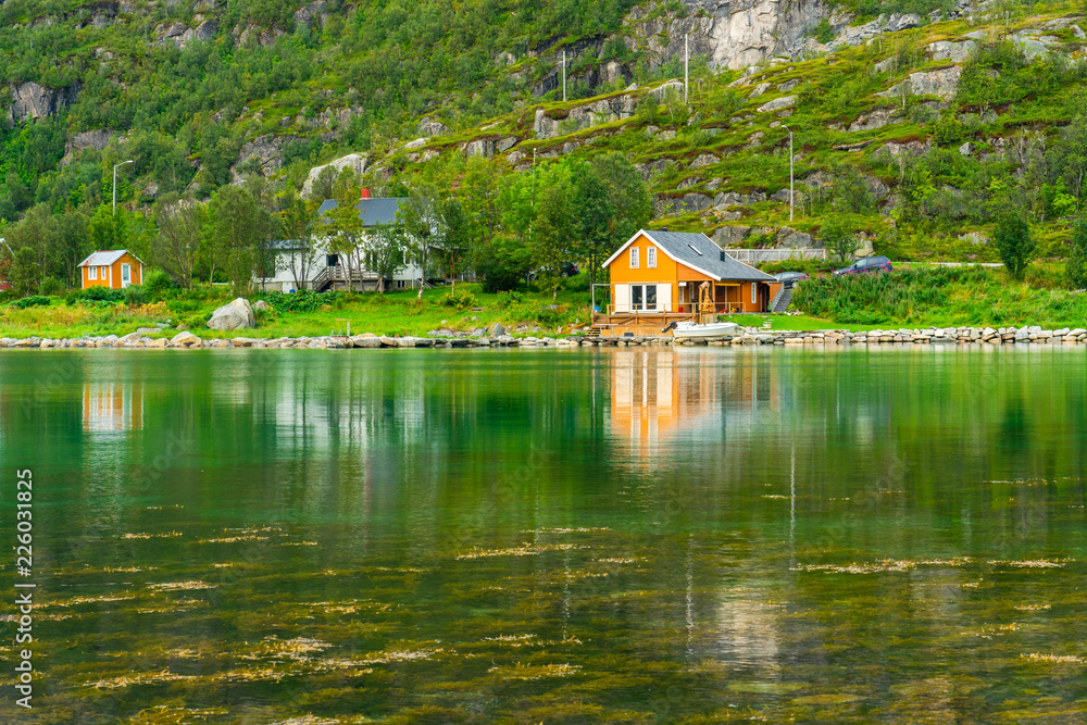 Obraz premium Typical Norwegian wooden huts in Ersfjordbotn village on the coast of Ersfjorden - beautiful fjord in Troms County, Norway