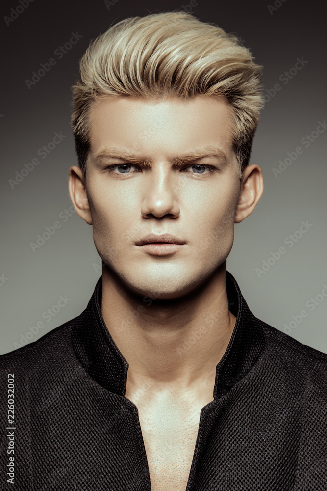 Obraz premium Handsome stripped blonde male model wearing black suit on white isolated font background