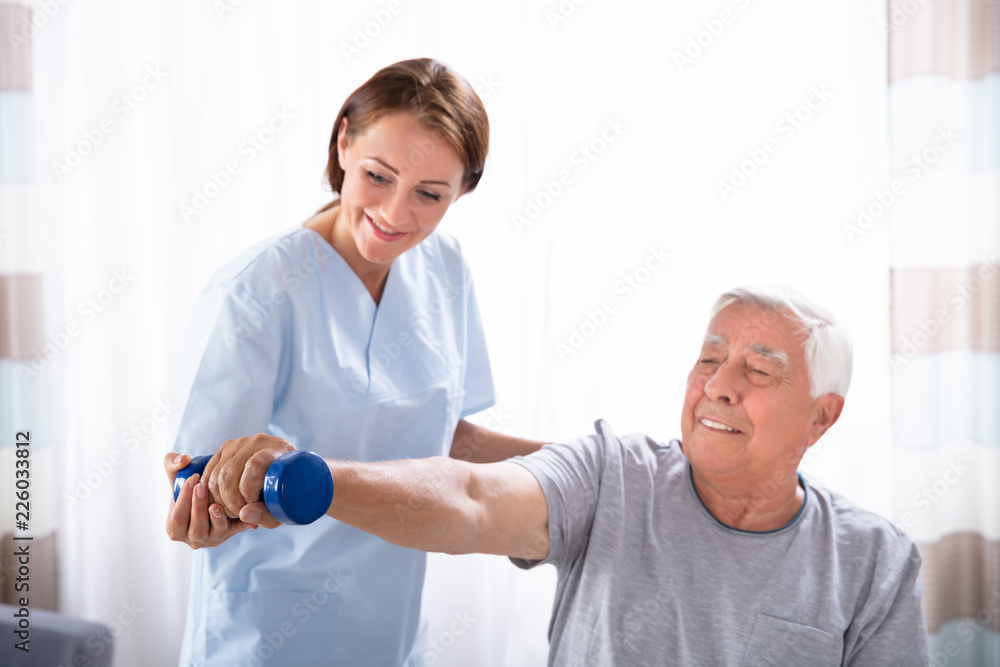 Nurse Helping Senior Man With Dumbbell Exercise Nurse Helping Senior Man With Dumbbell Exercise