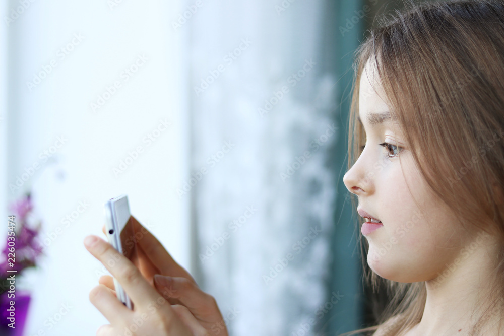Close up portrait of cute little girl looking at screen of digital tablet or phone with scared surprised face expression. Child internet safety and parenting control concept. Copy space Close up portrait of cute little girl looking at screen of digital tablet or phone with scared surprised face expression. Child internet safety and parenting control concept. Copy space