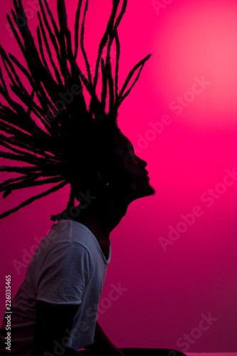 Canvas-taulu silhouette of african man with flying dreadlocks in profile on red background