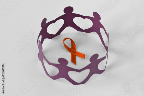 Paper people in a circle around orange ribbon on white background - Concept of leukemia awareness, kidney cancer association, multiple sclerosis and animal abuse photo