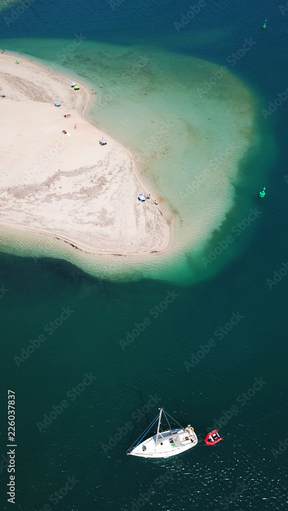 Aerial drone bird's eye view of famous and exotic sand tongue beach with clear emerald waters near castle of Santa Mavra in entrance of Lefkada island, Ionian, Greece