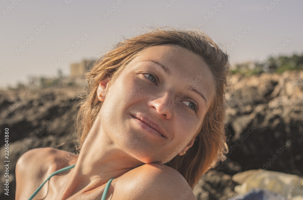 Portrait of a young pensive woman sunbathing at sunset