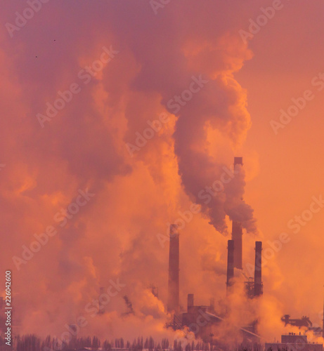 Smoke from the factory pipes against the dawn of the sun