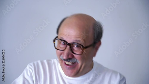 happy excited laughing facial emotion expression of senior 60s 70s year old man cloe up of him dancing in studio on grey background in face expression concept. 