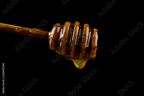 Honey dripping from dipper isolated on black background