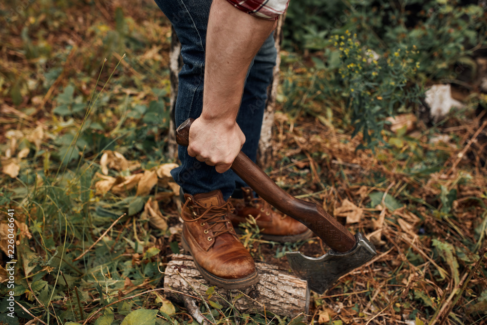 Man in jeans and checkered shirt holding old axe on stump with leg Stock  Photo | Adobe Stock