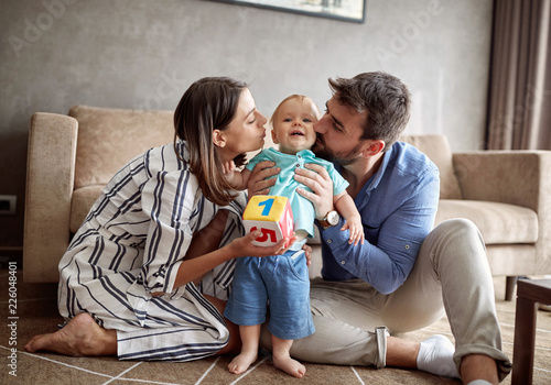 Lovely proud family - mother and father kissing their baby boy  . photo