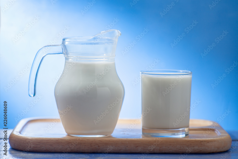 Splash of milk from the milk glass ,Morning milk, Glass jug and glass with milk on a wooden table on white background Splash of milk from the milk glass ,Morning milk, Glass jug and glass with milk on a wooden table on white background