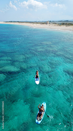 Aerial drone photo of couple practicing Stand Up Paddle or SUP in tropical exotic emerald and sapphire island sea