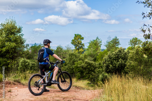 Male mountain biker on his emtb taking a break and looking down the trail