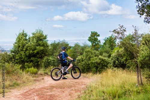 Electric mountain bike rider standing at the side of the road, taking a break