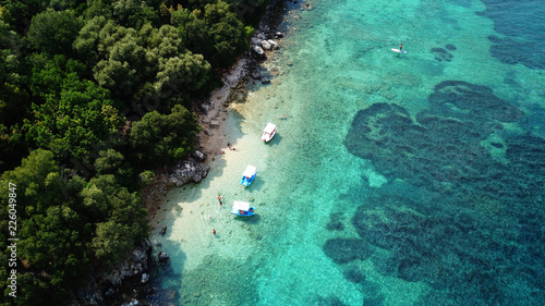 Aerial photo of iconic white cliff tropical bay forming a blue lagoon with deep turquoise clear ocean and docked small boats enjoying this unique paradise