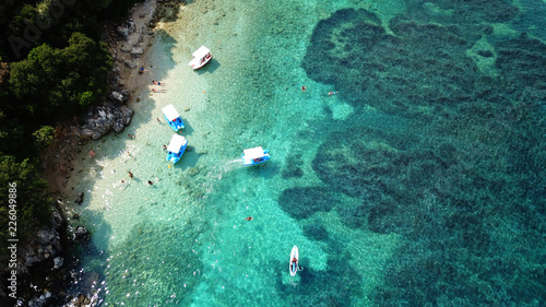 Aerial photo of iconic white cliff tropical bay forming a blue lagoon with deep turquoise clear ocean and docked small boats enjoying this unique paradise