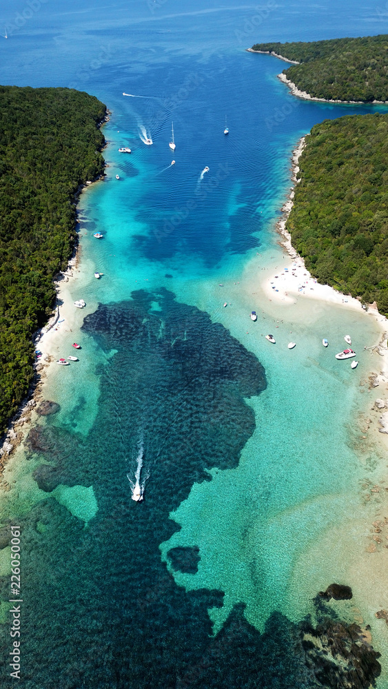 Aerial photo of tropical exotic paradise vegetated island with blue lagoon, white sandy beaches and turquoise sea with sail boats and yachts docked