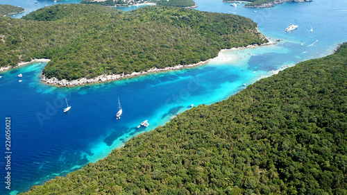 Aerial drone bird's eye view photo of iconic paradise sandy beach of blue lagoon with deep turquoise clear sea and pine trees in complex island of Mourtos in Sivota area, Epirus, Greece