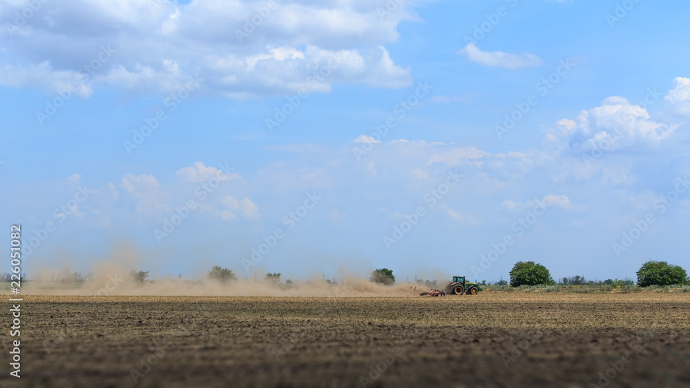 Obraz premium tractor plowing field on a hot summer day / agriculture field preparation for the following code