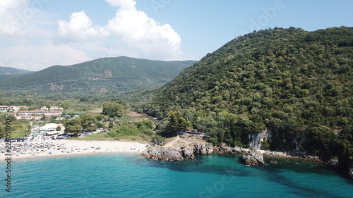 Aerial drone bird's eye view of popular beach of Karavostasi with beautiful clouds and turquoise sandy beach full of sunbeds at summertime, Epirus, Ionian, Greece © aerial-drone