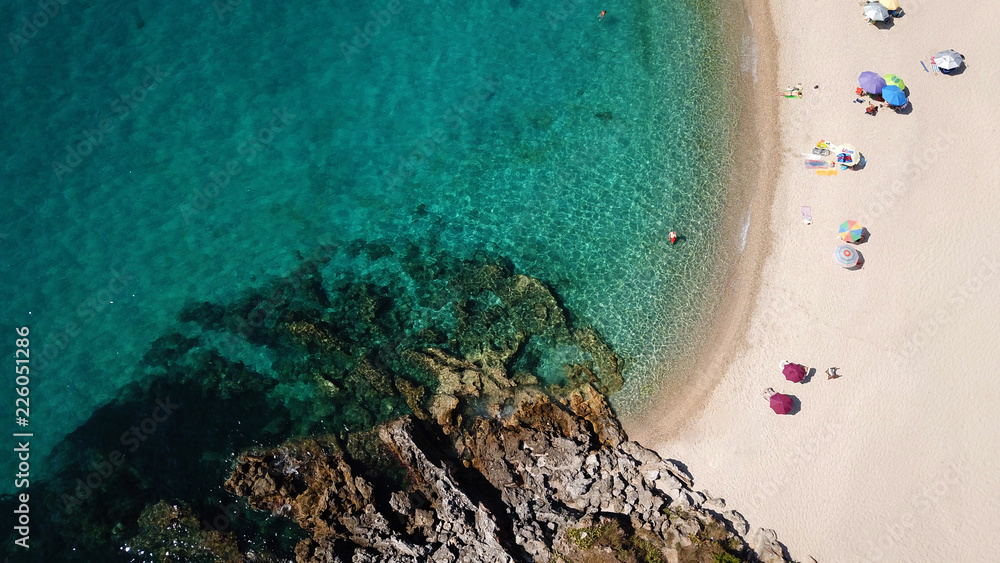 Aerial drone bird's eye view of popular beach of Karavostasi with beautiful clouds and turquoise sandy beach full of sunbeds at summertime, Epirus, Ionian, Greece