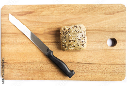 Bread with linseed, oats and sesame seeds next to a knife on a wooden board
