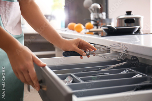 Photo Woman putting whisk into kitchen drawer