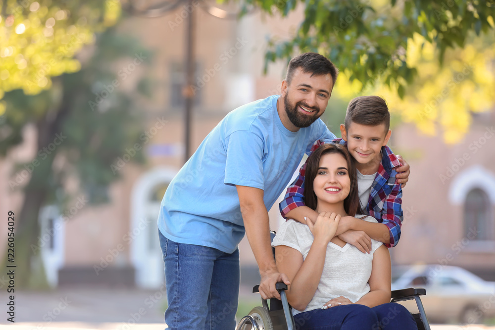 Young woman in wheelchair with her family walking outdoors Young woman in wheelchair with her family walking outdoors