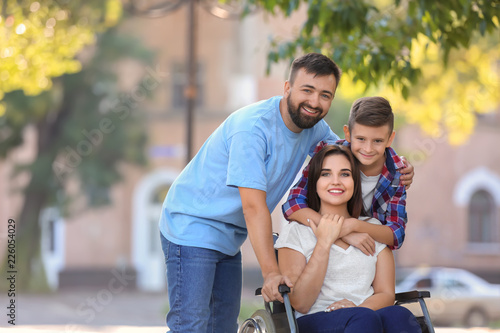 Young woman in wheelchair with her family walking outdoors