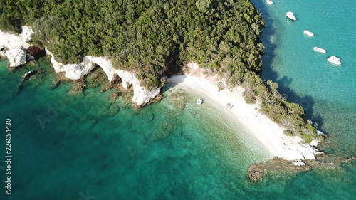 Aerial drone bird's eye view of popular beach of Zeri with beautiful emerald sandy beach full of sunbeds and sail boats at summer time, Epirus, Ionian, Greece