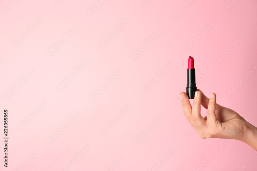 Woman holding bright lipstick on color background Woman holding bright lipstick on color background