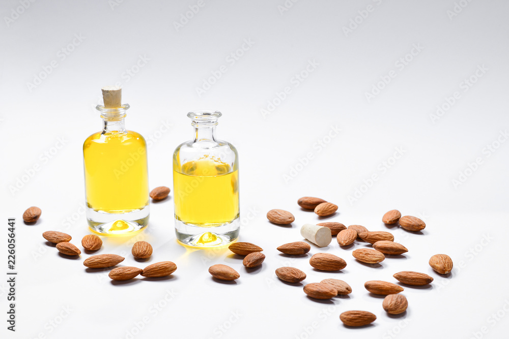 Bottles of almond oil and almonds on white background, copyspace. Bottles of almond oil and almonds on white background, copyspace.
