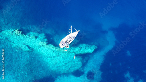 Aerial drone bird's eye view photo of sail boats docked in tropical caribbean paradise bay with white rock caves and turquoise clear sea