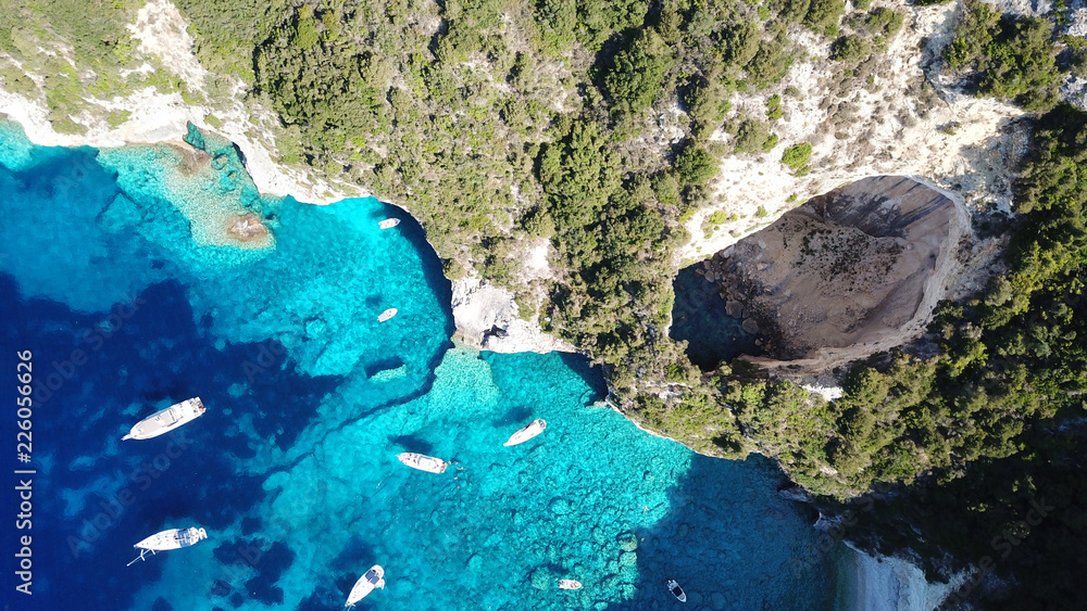 Aerial drone bird's eye view photo of iconic tropical rocky paradise bay called blue lagoon with caves and turquoise clear waters visited by sail boats, island of Paxos, Ionian, Greece