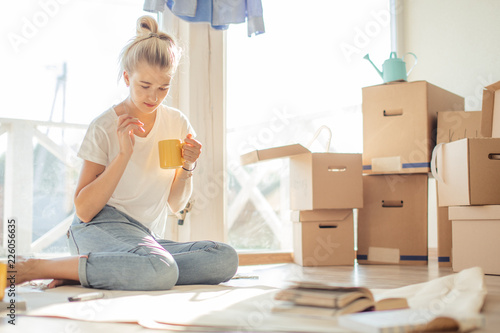 Portrait of smiling woman sitting on floor of new house making plan to furniture their home on paper photo