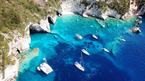 Aerial drone photo of sail boats anchored in tropical Caribbean paradise bay with white rock caves and turquoise clear sea photo